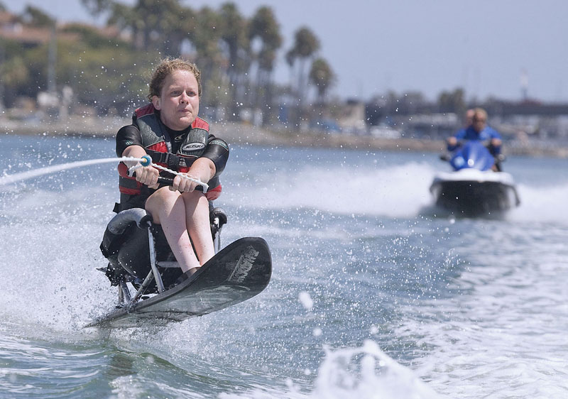 An adaptive water skier on Big Bear Lake with two people riding a jet ski in the background