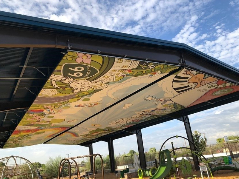 Large metal canopy with painting underneath featuring a sky, mountains, a dog and a route 99 sign