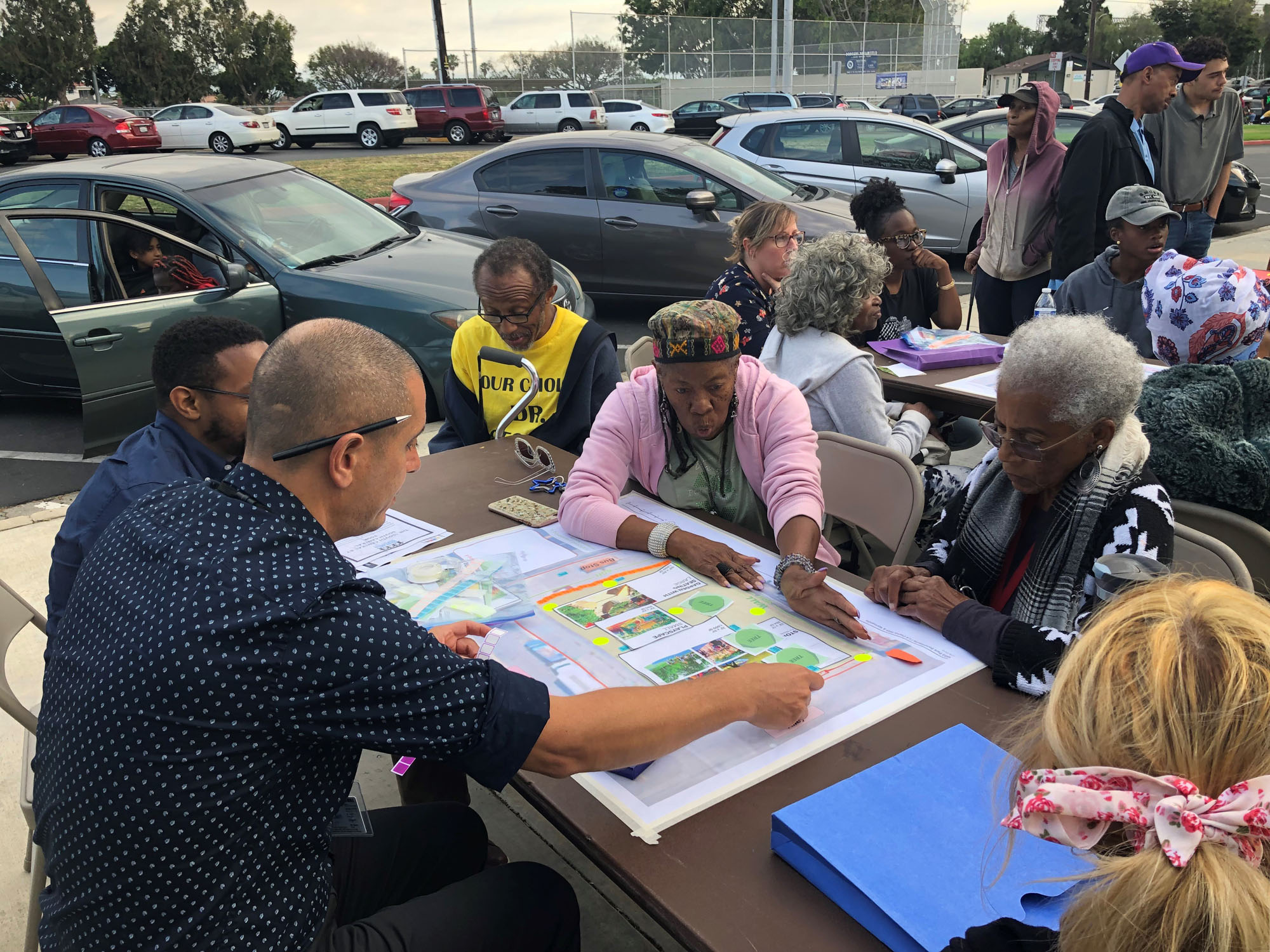 People seated at table in a parking lot reviewing a design plan for a new park