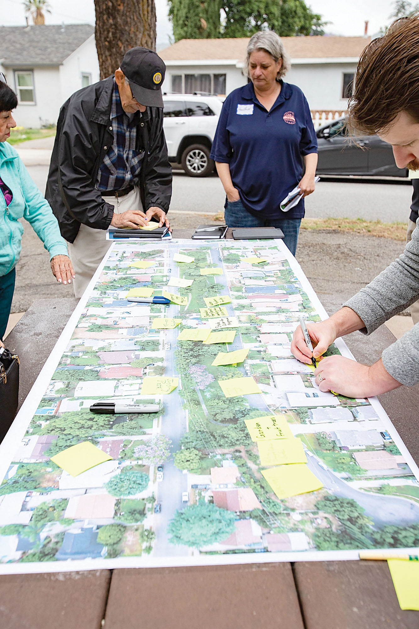 People gathered around a picnic table adding post-it notes to a large printed aerial photograph map